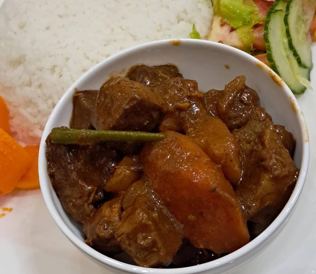 Rich beef stew with rice, vegetables and salad